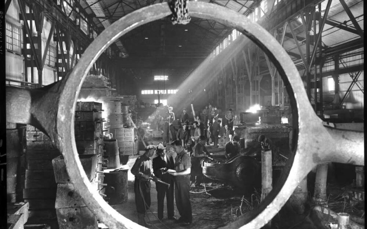 Photograph of employees at BHP steelworks, Newcastle. The dressing end of the steel foundry, viewed through a cast steel tilting frame of a slag pot.